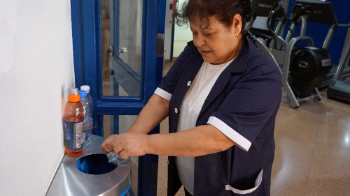 Halloun Wehbe, from Hospitality Department, squeezing PET water bottles one by one and inserting them into the Bottles and Cans recycling bin